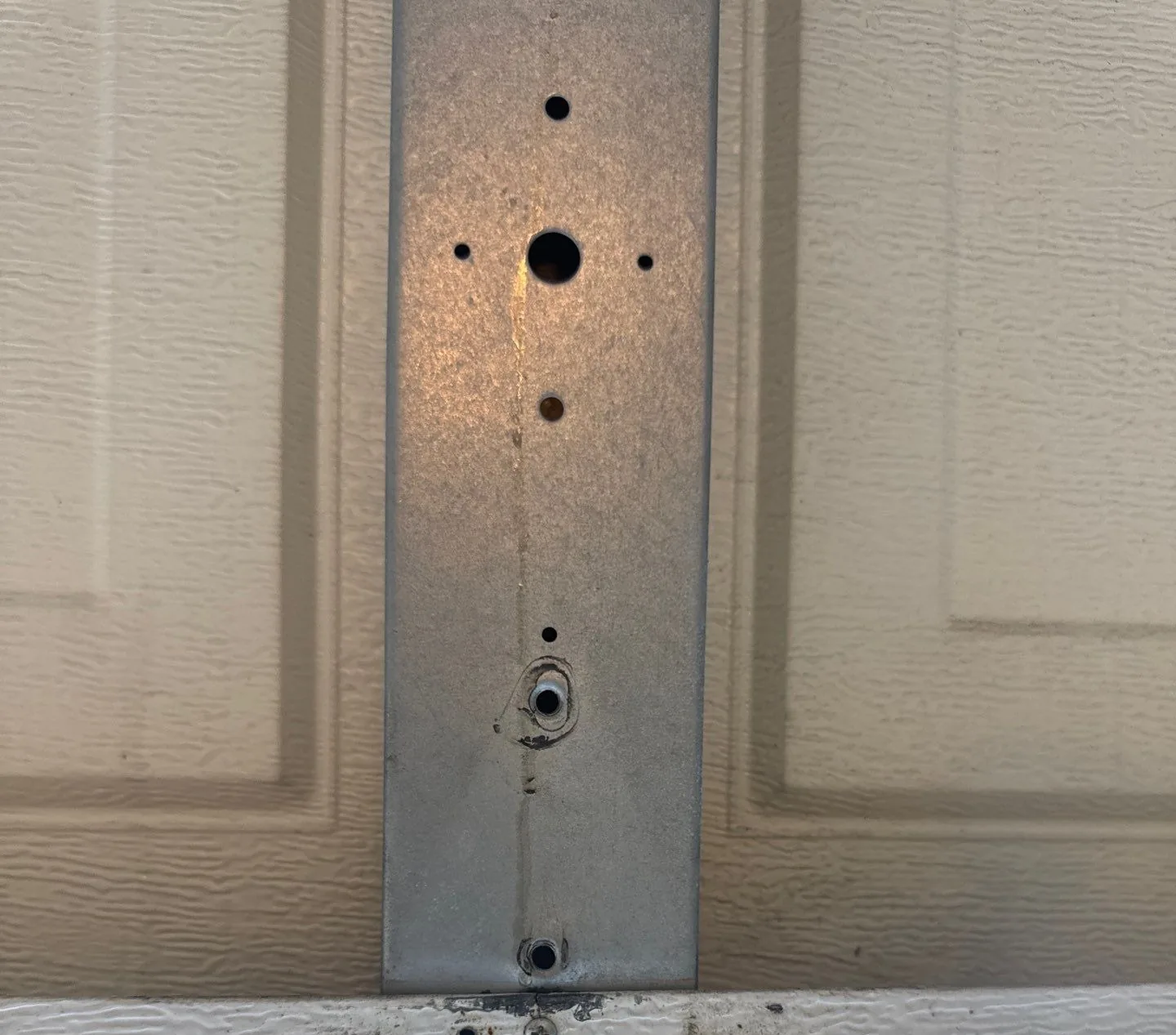 Cracked garage door bottom bracket before repair in Fremont.